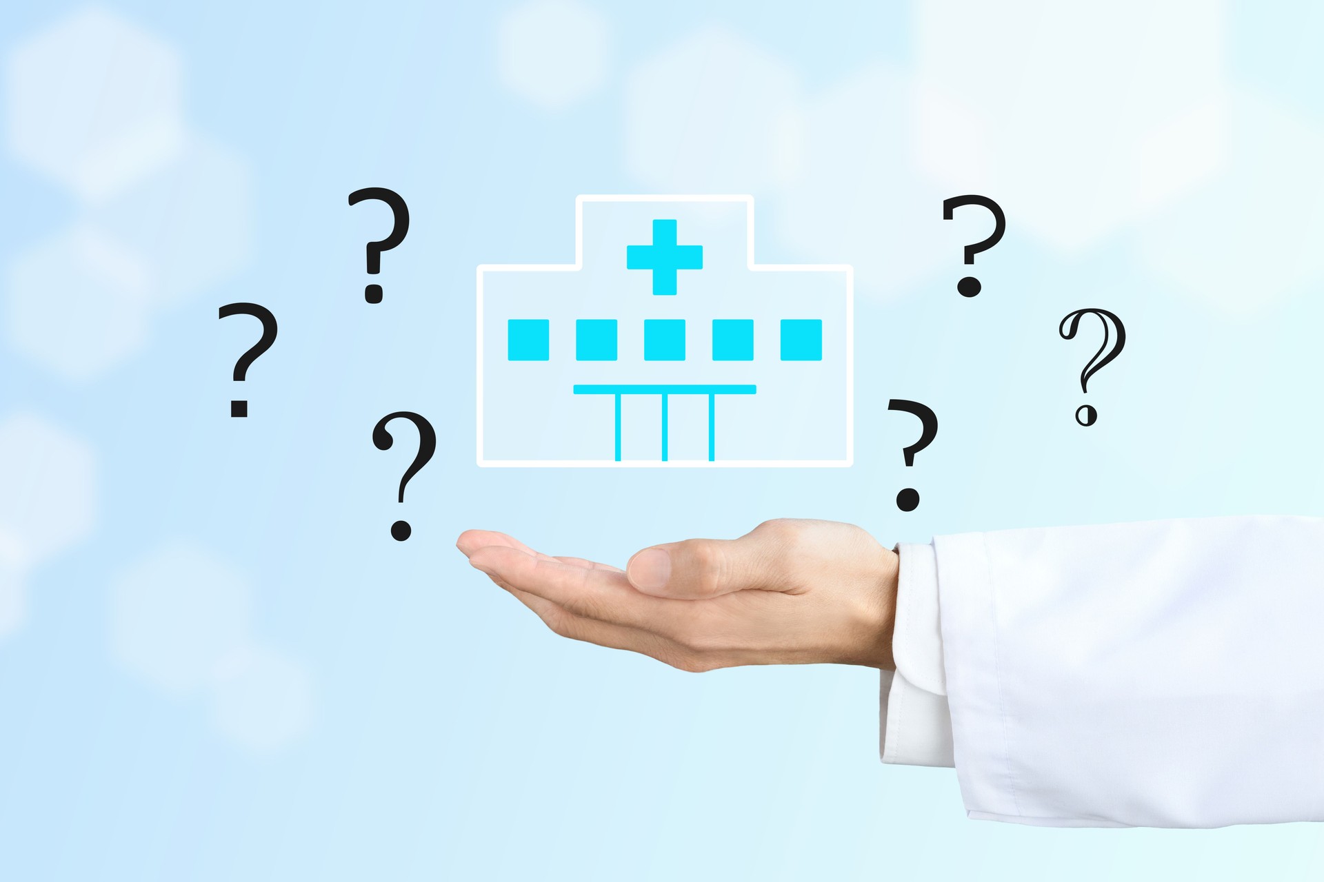 Doctor's hand holding up a hospital icon and question marks